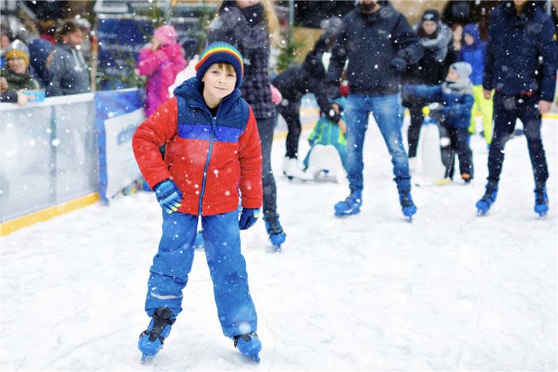 A boy ice skates outside during a winter festival.