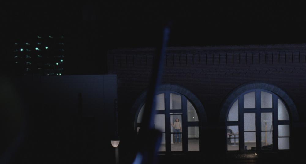 Blood Simple screengrab showing the exterior windows of Abby's Apartment at night