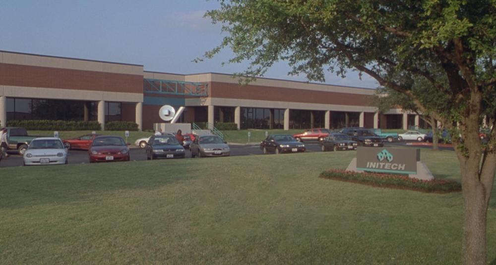 Office Space screengrab showing the exterior, parking lot and sign of Initech offices