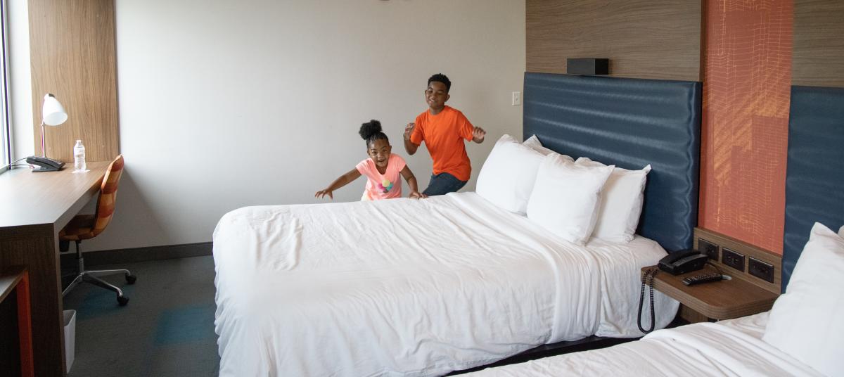 two children play on a bed at a Wichita hotel