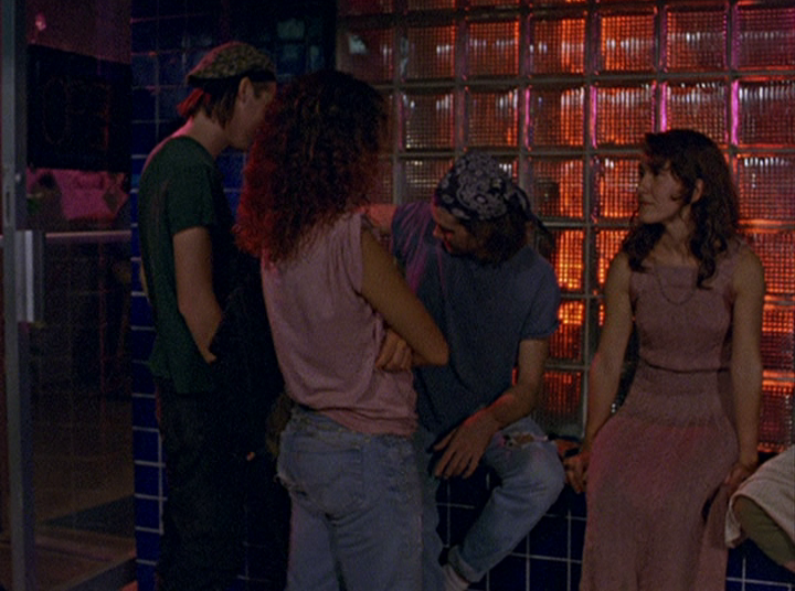 Slacker screengrab, shows a group of people talking inside the Blue Bayou Club. A wall of glass bricks is behind the people