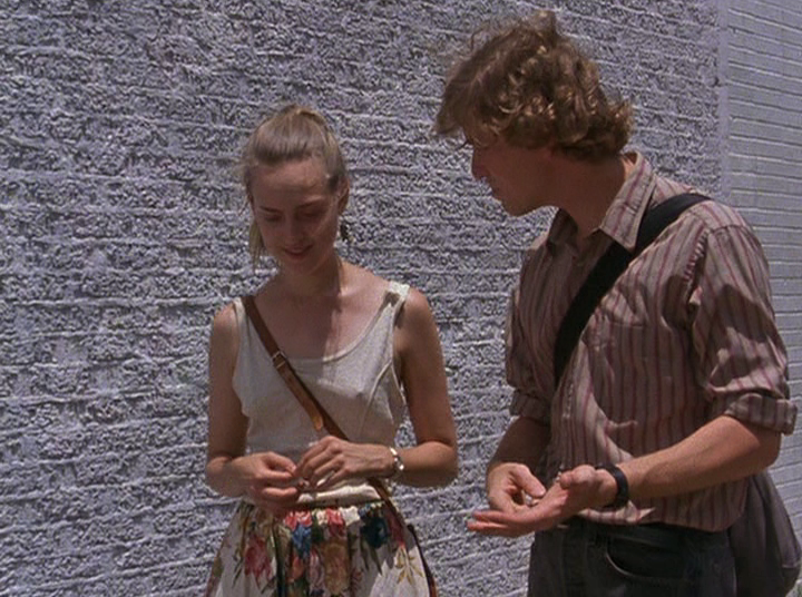 Slacker screengrab, showing a man and woman walking by a white brick wall