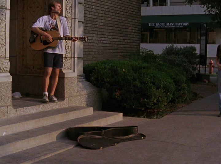 Slacker screengrab, a man plays guitar outside a church on Guadalupe Street