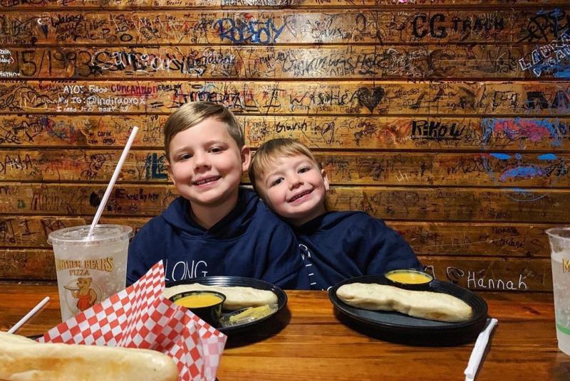 Two little boys smiling in a booth at Mother Bear's