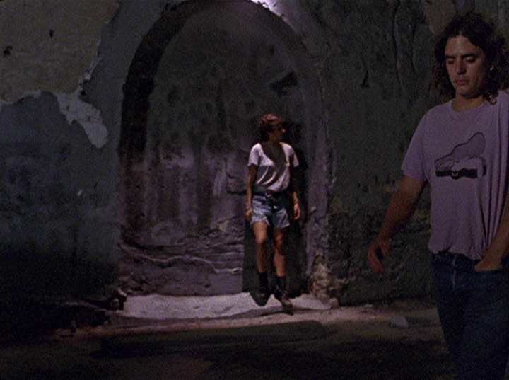 Slacker screengrab, showing a man near the camera and a woman standing in a dark archway
