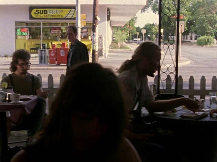 Slacker screengrab showing people on a patio during the day. Behind them, a Subway is visible at street level