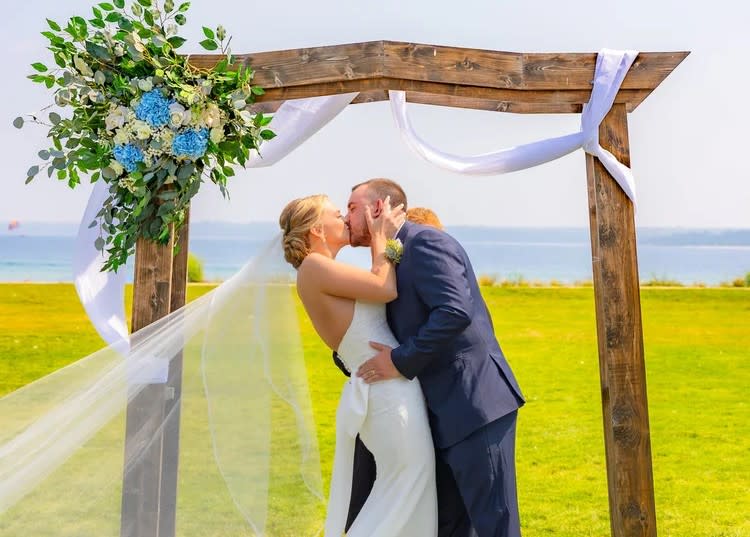 Bride and groom kissing under altar on the waterfront lawn at Mackinac Island’s Mission Point Resort