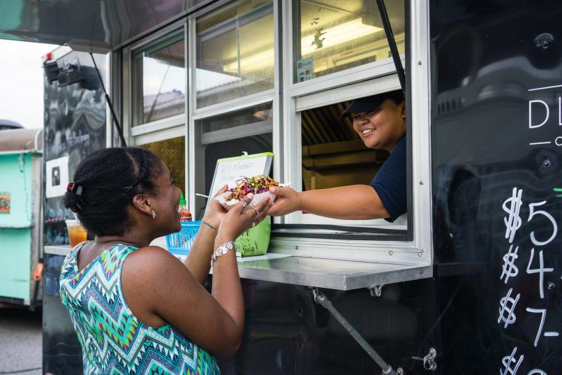 A woman handing a meal over to a customer through a food truck window