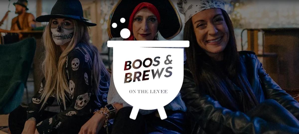 Image is of 3 women wearing costumes with a caldron in front of them that say's Boos & Brews on the Levee.