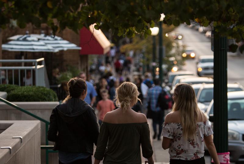 Three women walking down Kirkwood Avenue on a fall evening