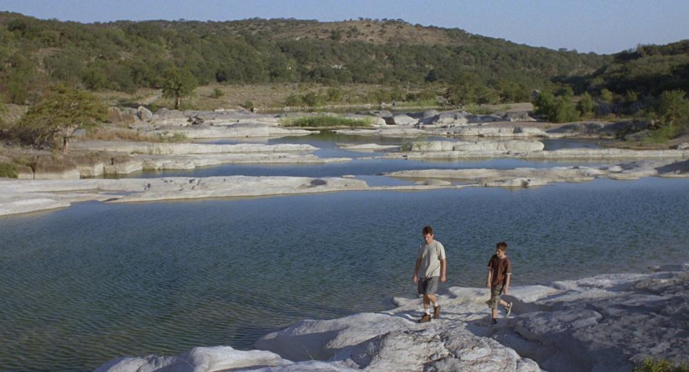 Boyhood screengrab showing Mason and his dad walking in front of the water at Pedernales Falls State Park