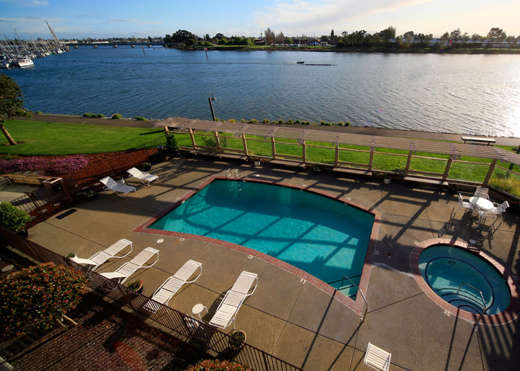 The pool at the Best Western Plus Bayside Hotel & Executive Inn in Oakland surrounded by lounge chairs, tables, and a gorgeous view of the bay.