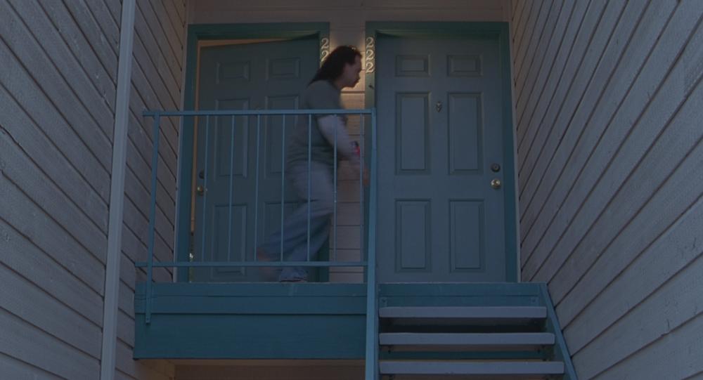 Office Space screengrab, showing a man walking from one blue apartment door to his neighbor's door