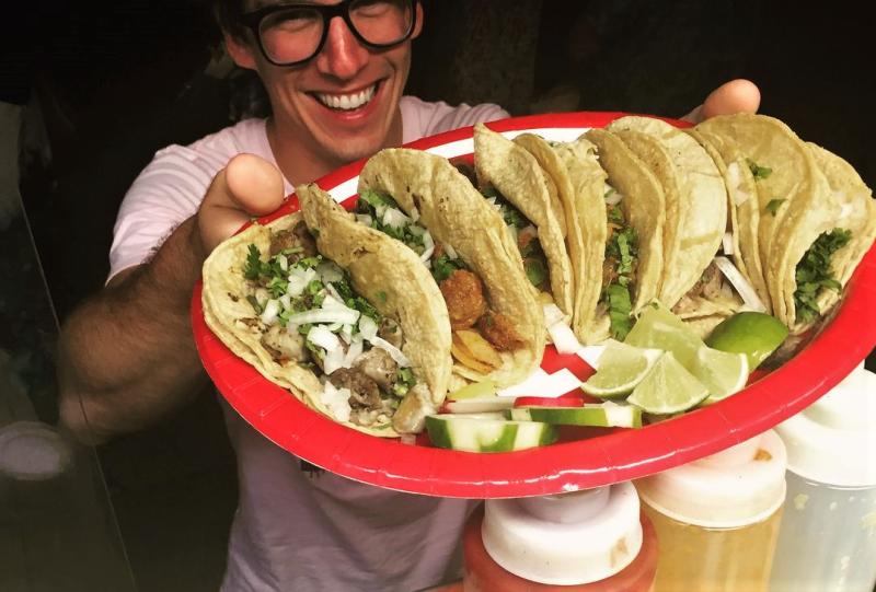 Man serving platter of tacos from Pili's Party Taco Truck