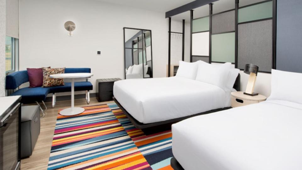 Two queen beds in hotel room with colorful rug.