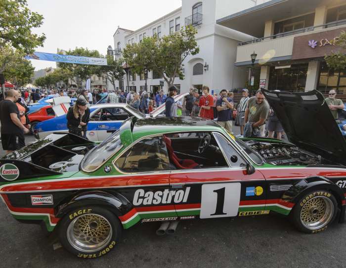 This is an image of a Castrol race car displayed along Alvarado Street in Monterey for Monterey Car Week. Spectators look in to the open hood