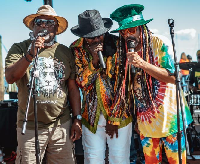 Three black men singing on a stage at a festival