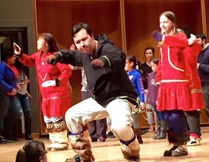 An Inupiaq dancer on stage in a concert hall
