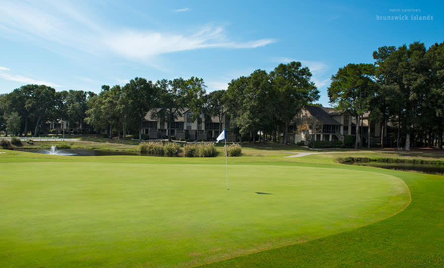 a golf course green at Sea Trail Golf Resort with a view of condos in the background