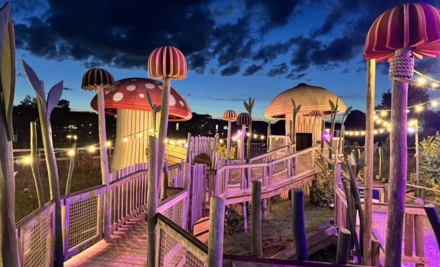 Colourfully illuminated fantasy-themed play area at dusk at Fairytale Farm in the Cotswolds.