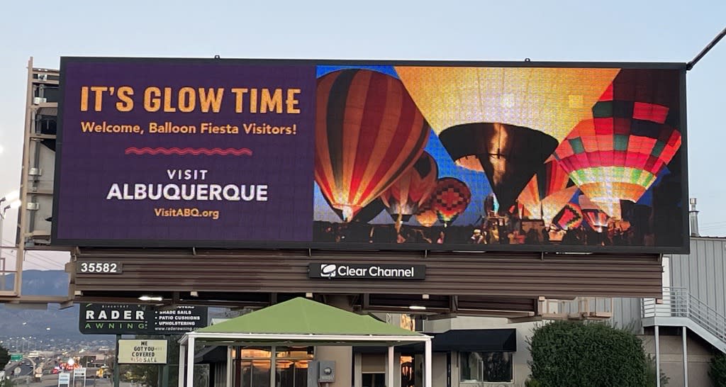 A picture of a Visit ABQ billboard at Paseo and Jefferson reading "it's glow time" with picture from a balloon glow.