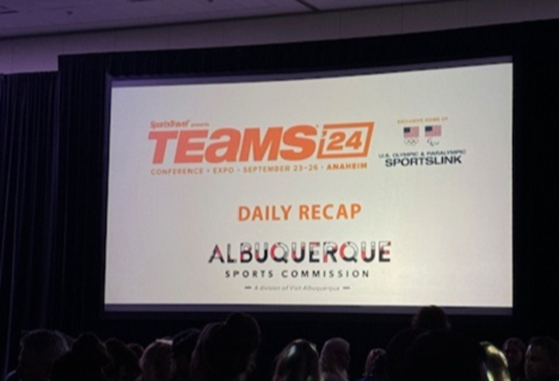 A photo of a slide at the 2024 TEAMS Conference showing the Visit Albuquerque logo on a daily recap.
