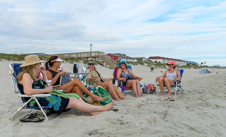 a group of women sitting in beach chairs on the beach