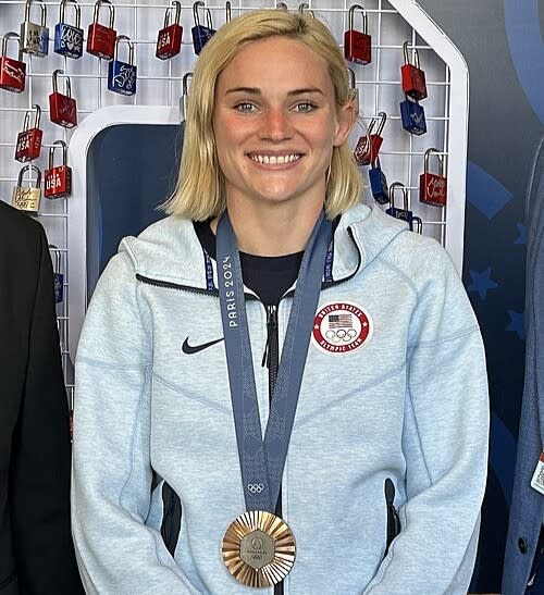 Olympic rugby player Sammy Sullivan smiles while wearing Team USA warm-up apparel and her Paris 2024 Olympic medal on a navy lanyard.