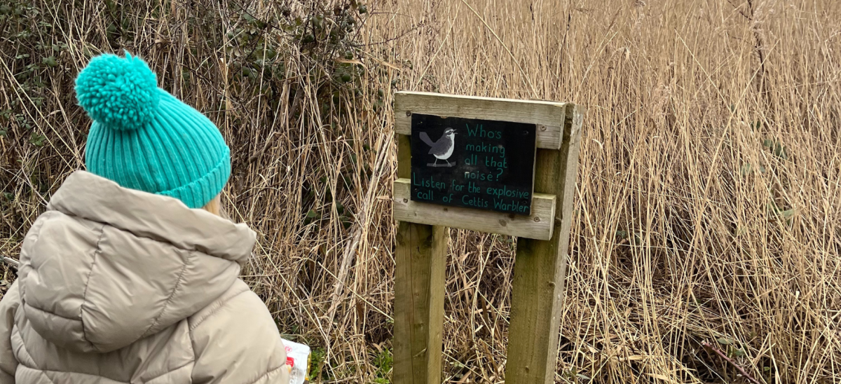 Girl looking at bird sign at RSPB Radiploe Lake in the winter