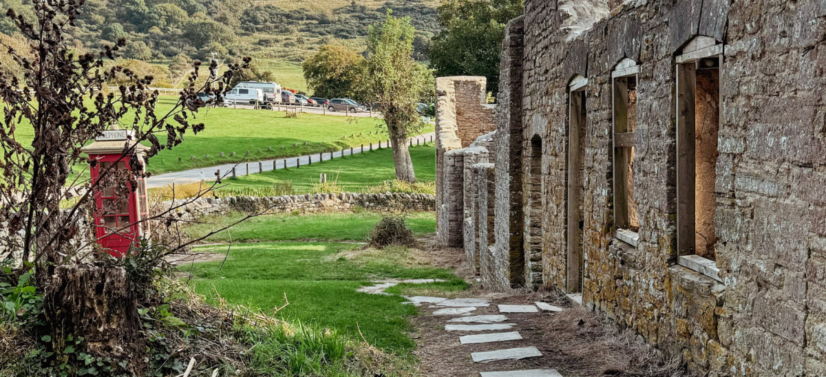 image shows a row of houses in ruin, with a red postbox on the left