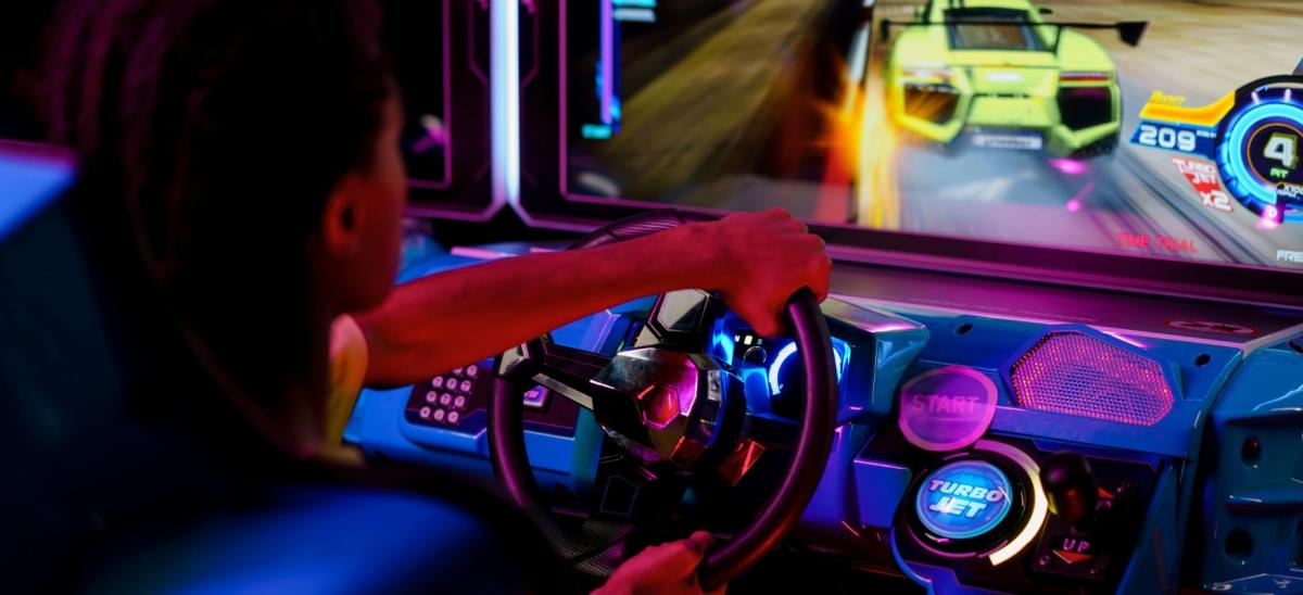 A teenage boy playing on a video game in an amusement arcade