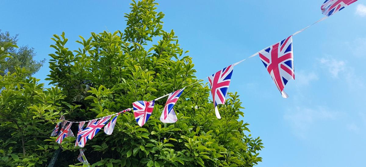 Union Flag bunting in front of a tree with blue sky behind