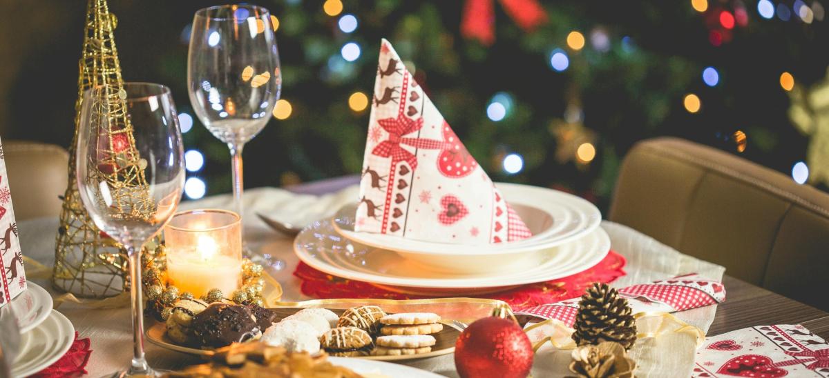 A Christmas dinner table with decorations, plates, wine glasses and biscuits
