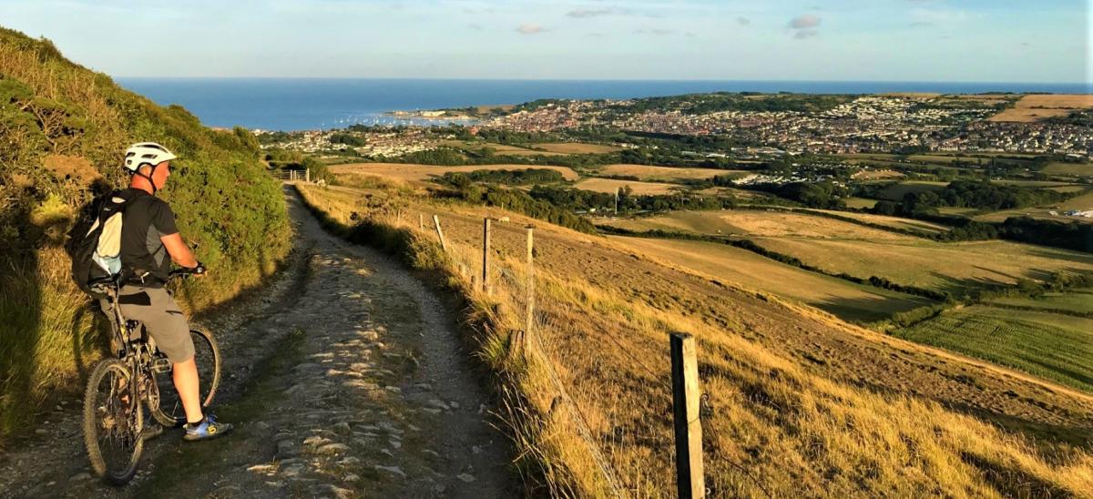 Male cyclist on the Purbeck Ridge looking towards Swanage in Dorset