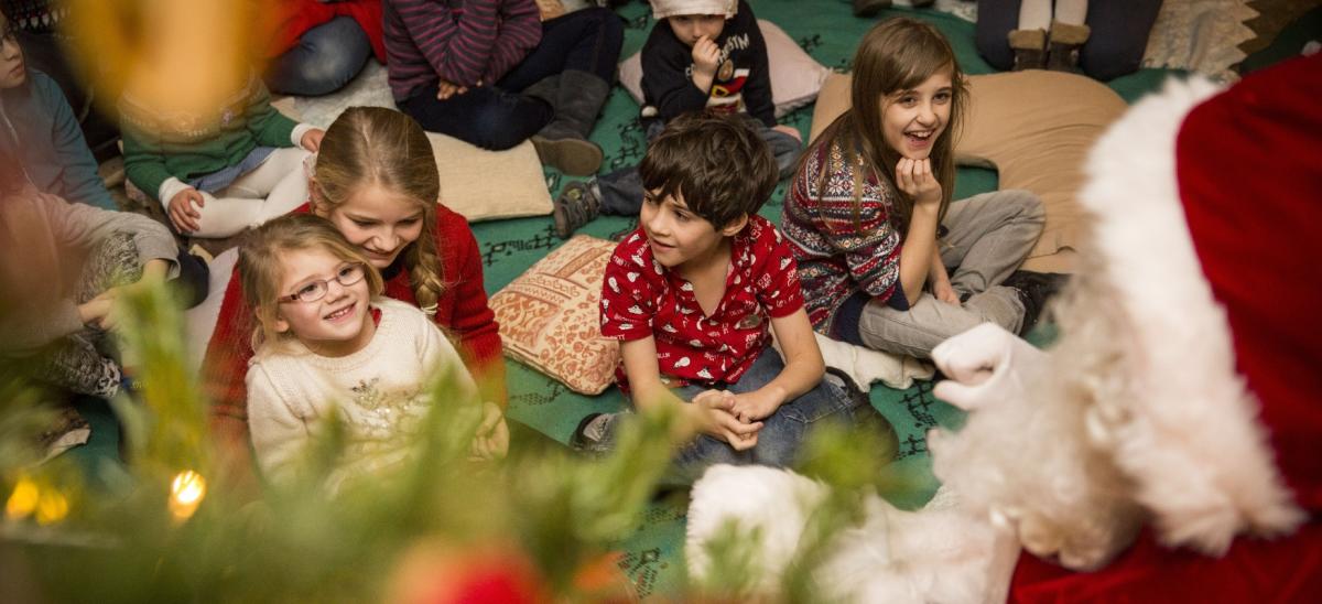 Children sitting on the floor listening to stories being told by Father Christmas