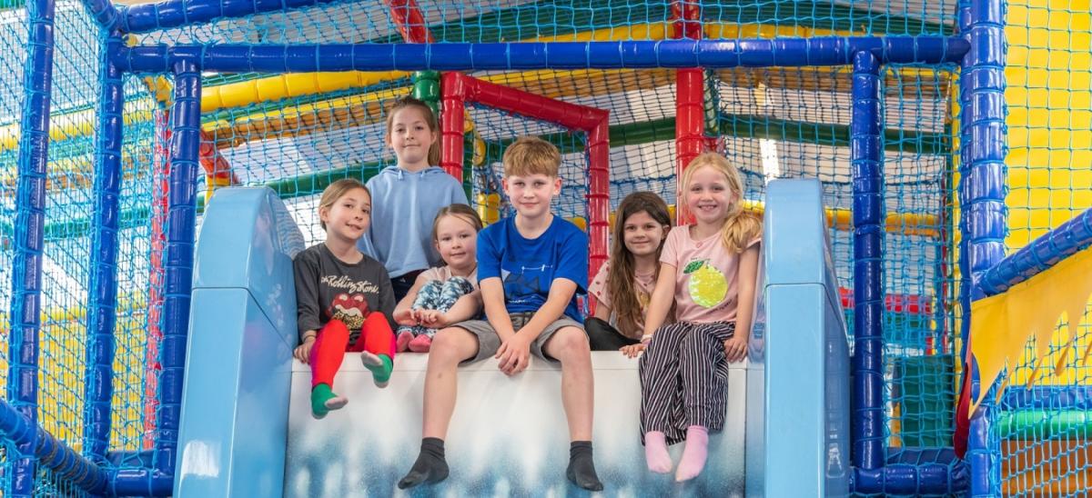 Six children sitting on top of a slide at Seals Cove The Reef soft play area in Bridport