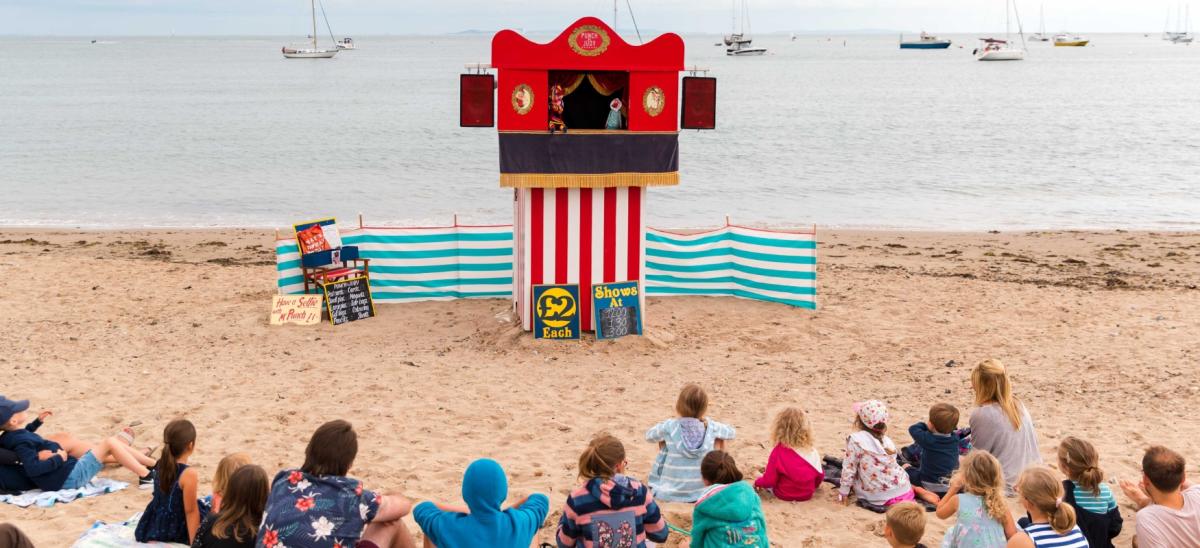 Children and families watching the Punch and Judy Show on Swanage Beach in Dorset