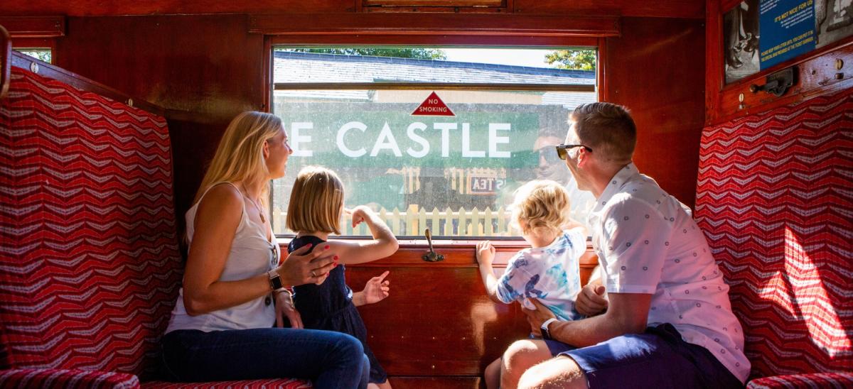 Two adults and two children sitting inside one of the train carriages on the Swanage Railway