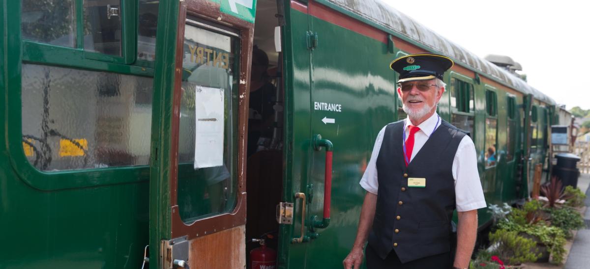A guard standing next to one of the train carriages on the Swanage Railway in Dorset