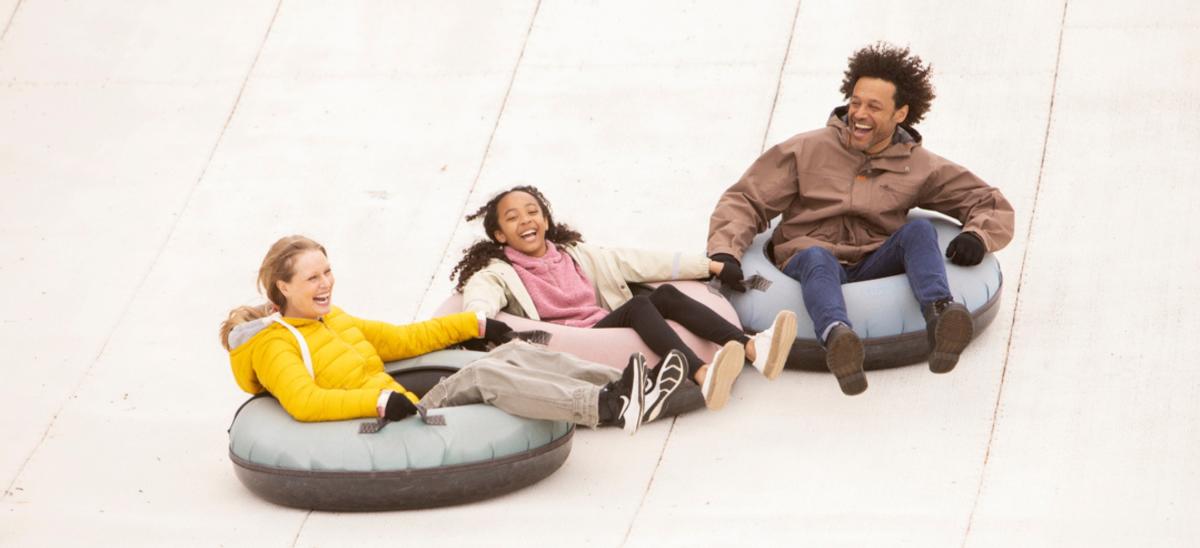 Three people sitting in ringos sliding down the ski slope at Warmwell Holiday Park in Dorset