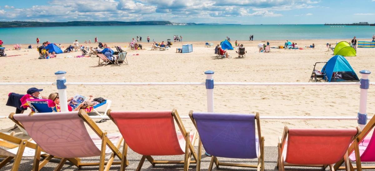 Colourful deckchair on the promenade at Weymouth Beach, looking onto the beach