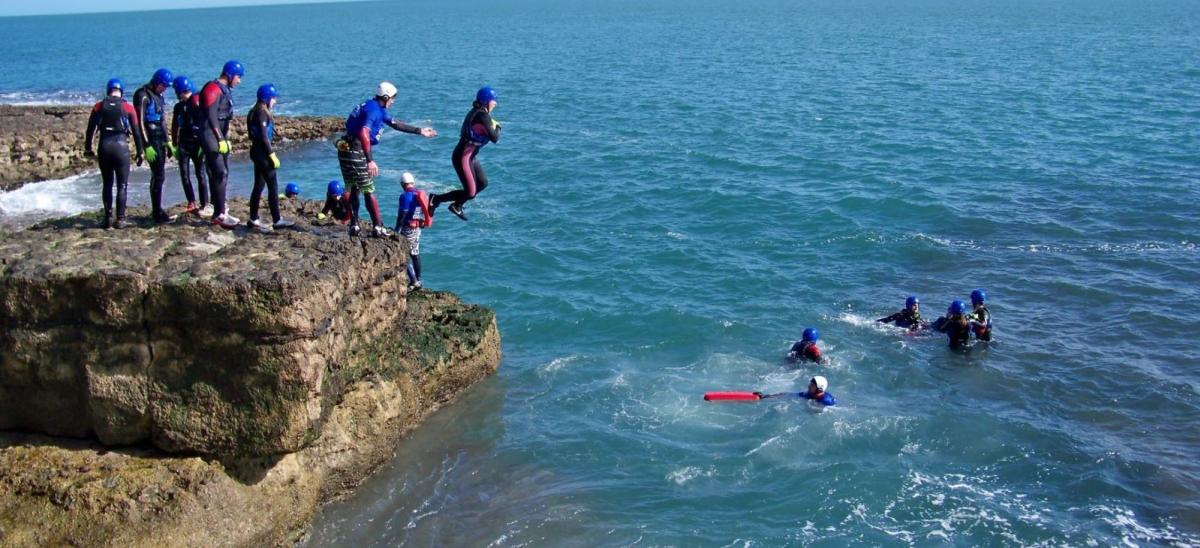 Group of people jumping into the sea part of a coasteering activity