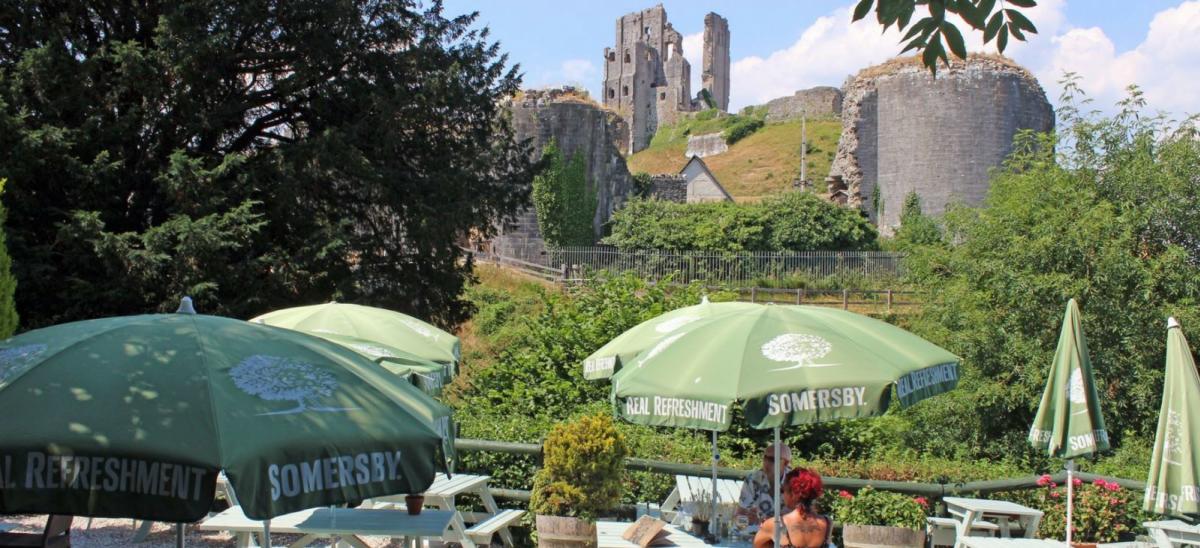 Outside tables at The Greyhound Inn with Corfe Castle in the background, Dorset