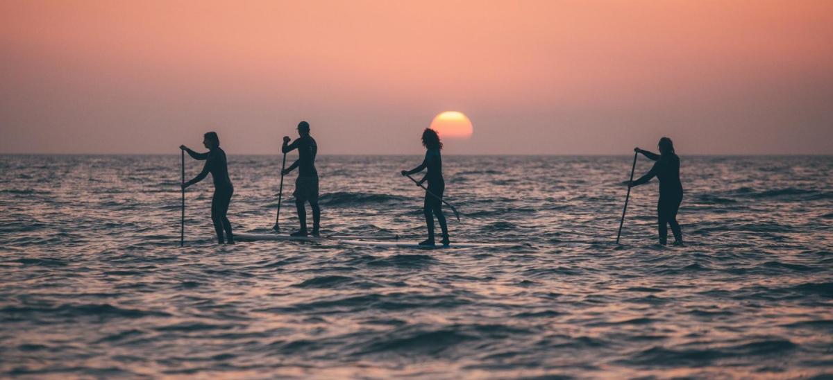 Four people stand up paddleboarding in Swanage Bay