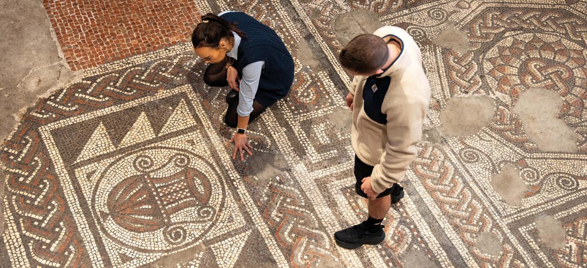 Two people looking at the Roman mosaic at Dorset Museum & Art Gallery