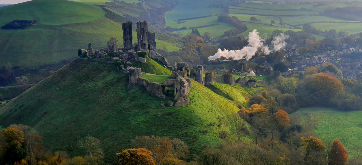 Autumnal picture of Corfe Castle with the steam train puffing past