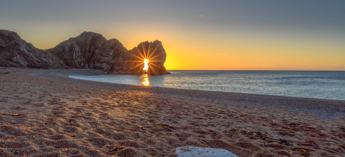Sun rising through Durdle Door arch in December