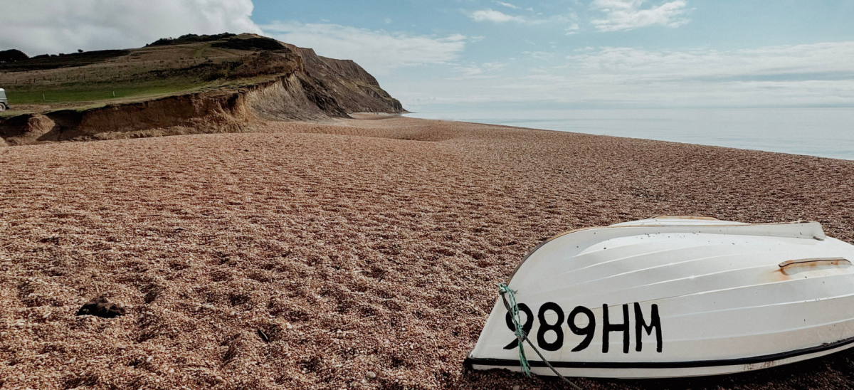 Looking east on Seatown Beach with white, upturned boat in foreground