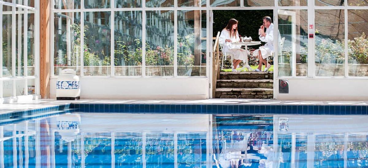 Indoor swimming pool and two people eating afternoon tea at Summer Lodge Country House Hotel and Spa