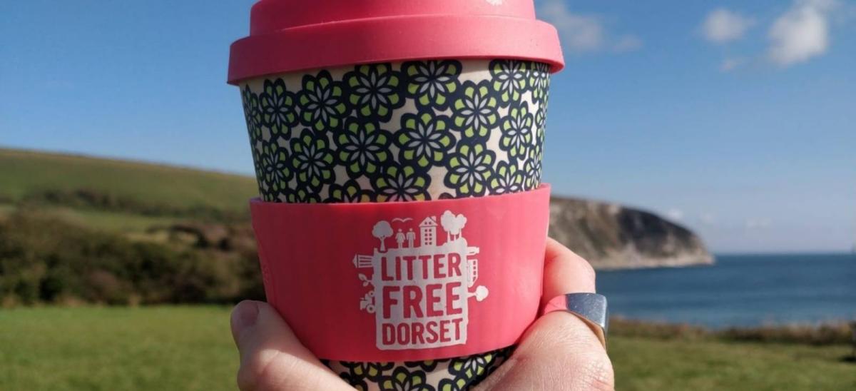 A person holding a Litter Free Dorset reusable coffee cup